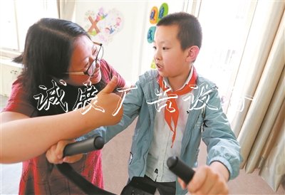 在無(wú)錫市廣新小學(xué)融合教育資源中心，梁溪區(qū)特教指導(dǎo)中心資源教師陳向華指導(dǎo)小過(guò)進(jìn)行康復(fù)訓(xùn)練，夸贊他有進(jìn)步。