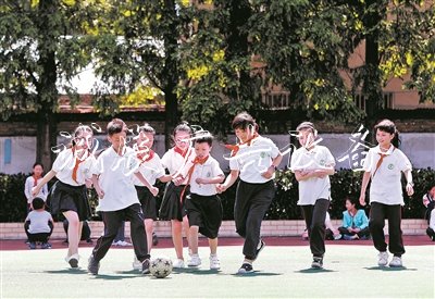在無(wú)錫市廣新小學(xué)操場(chǎng)上，隨班就讀學(xué)生小瑩、小俊和同學(xué)們一起踢足球。陽(yáng)光下，孩子們臉上綻放出燦爛的笑容。