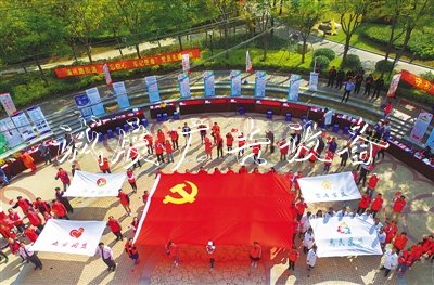 2019年10月19日，上海開展“不忘初心、牢記使命”黨員志愿者先鋒行動，“兩新”黨員志愿者在公園廣場托起一面黨旗。? 光明日報 圖